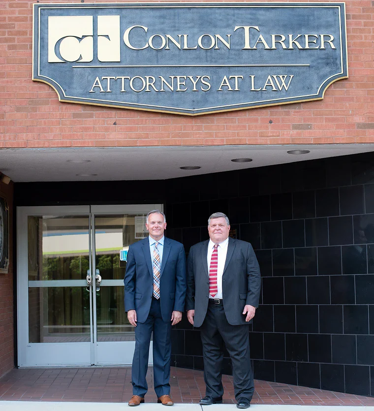 Three men in suits walk toward the Butler County Government Center. The scene is black and white, conveying a formal, serious atmosphere.
