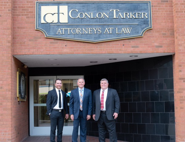 Photo of the firm's three attorneys at the front door of their office