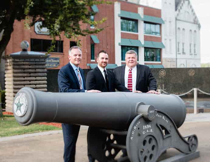 Photo of the firm's attorneys standing next to a vintage cannon